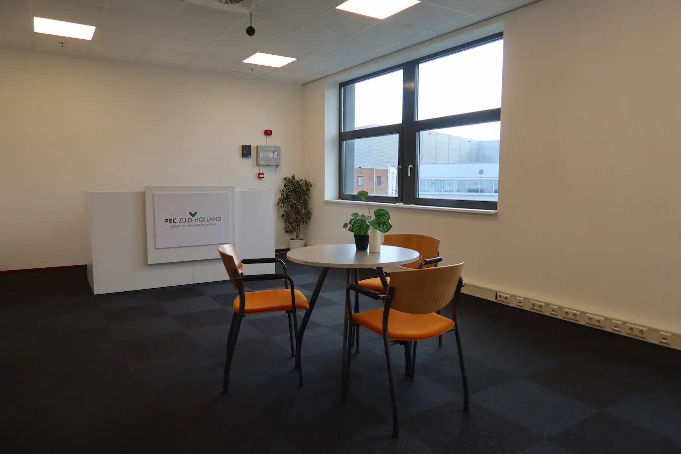 Een opleidings ruimte met drie stoelen en het logo van PEC zuid-holland
